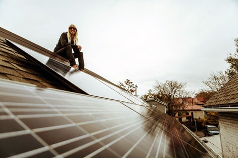 Woman sitting on a roof with solar panels.